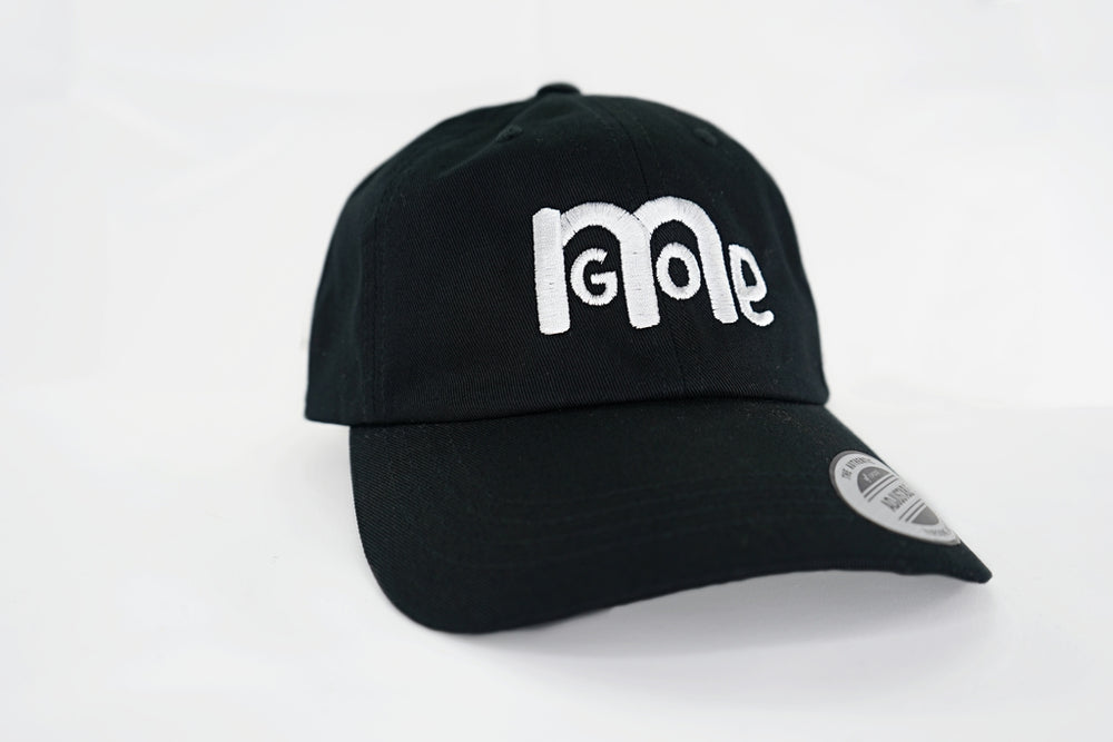 The forever popular Black 6 panel unstructured Dad Hat has Black curved under visor and antique Brass buckle closure. Embroidered in White is the GODinme Logo on front and GODinme name on left side.