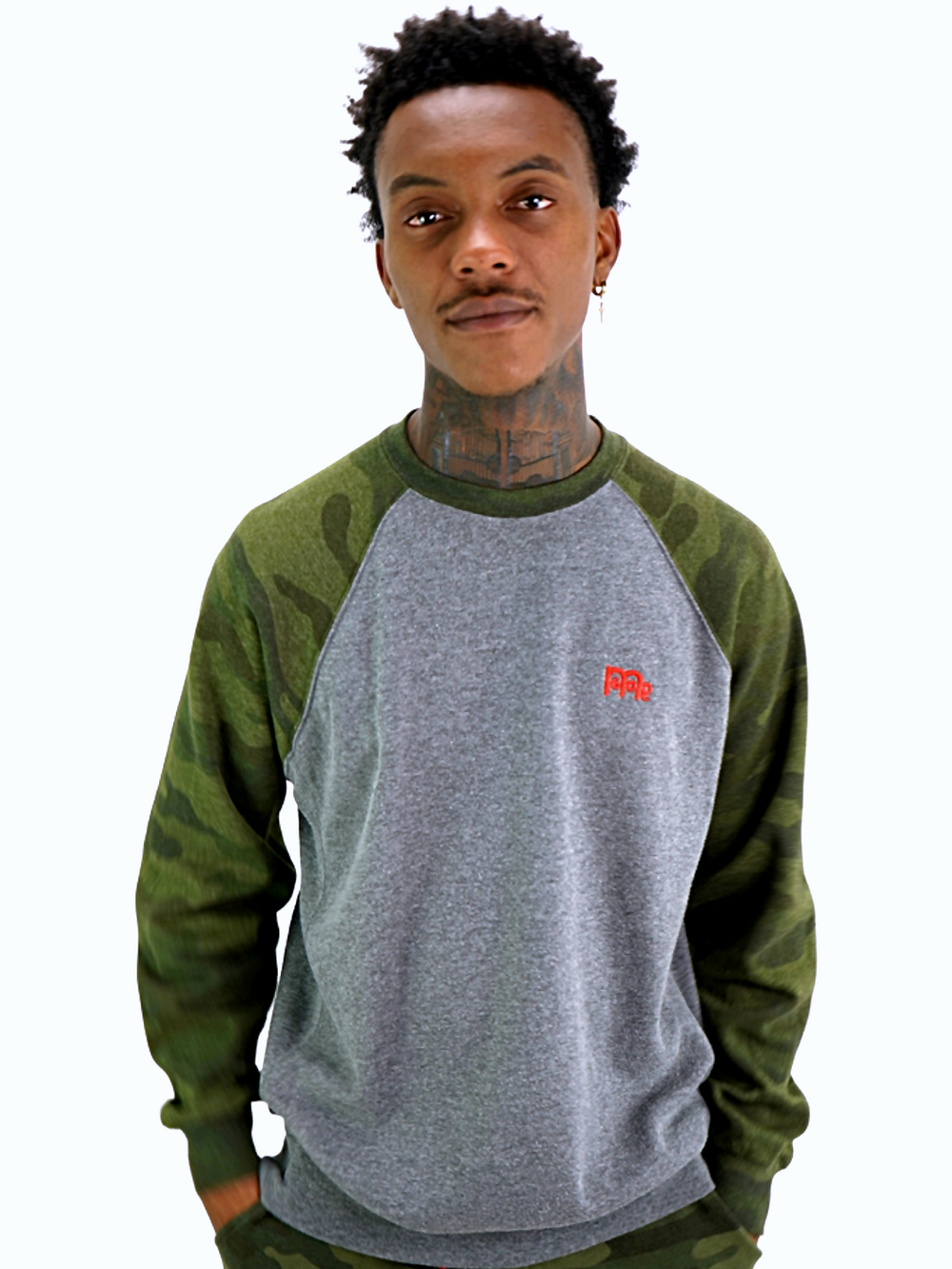 Model wearing a heather grey GODinme crewneck sweater with green camouflage raglan sleeves and GODinme logo on the chest.