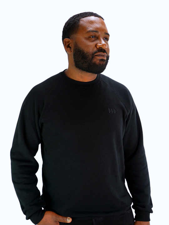 Model wearing long sleeve Black GODinme Crewneck Sweater with same color embroidered GODinme signature logo on front.