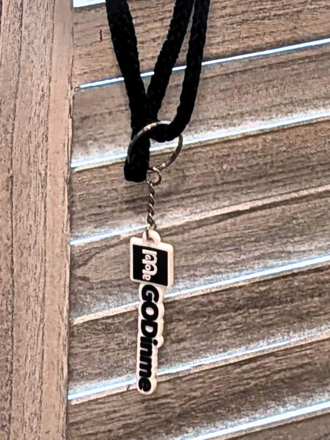 Close-up of GODinme keychain attached to drawstring backpack.