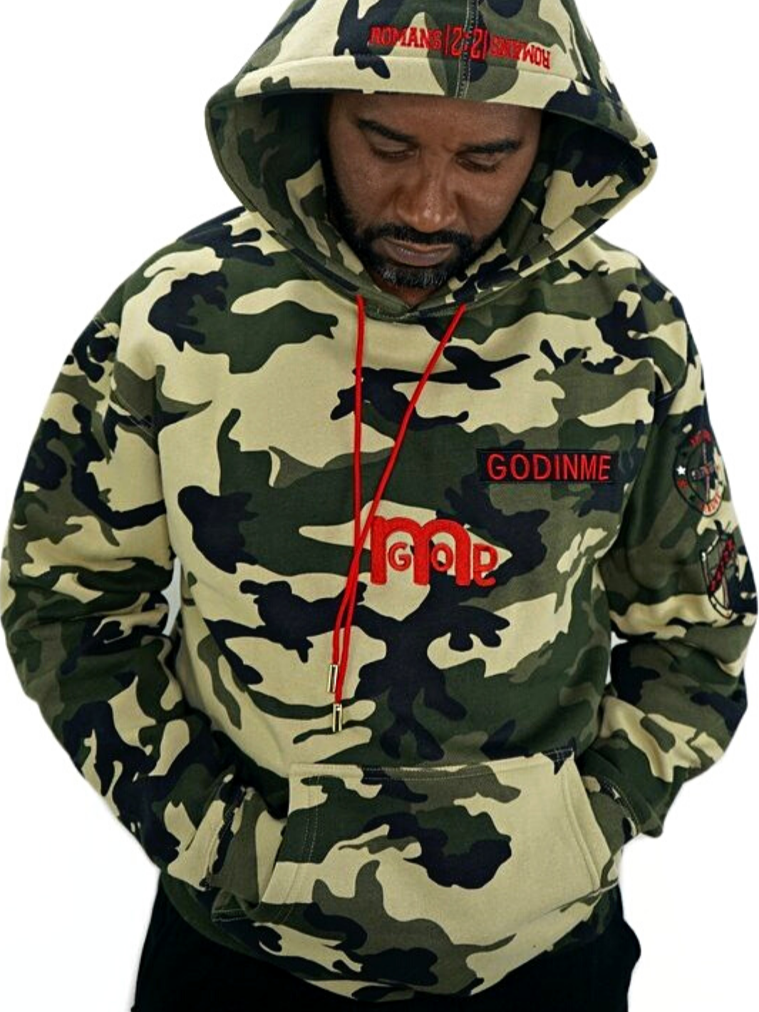 Male model wearing a camouflage pullover hoodie with a big bold red GODinme logo mid chest and embroidered  in red ROMANS 12 : 21 on hood. 