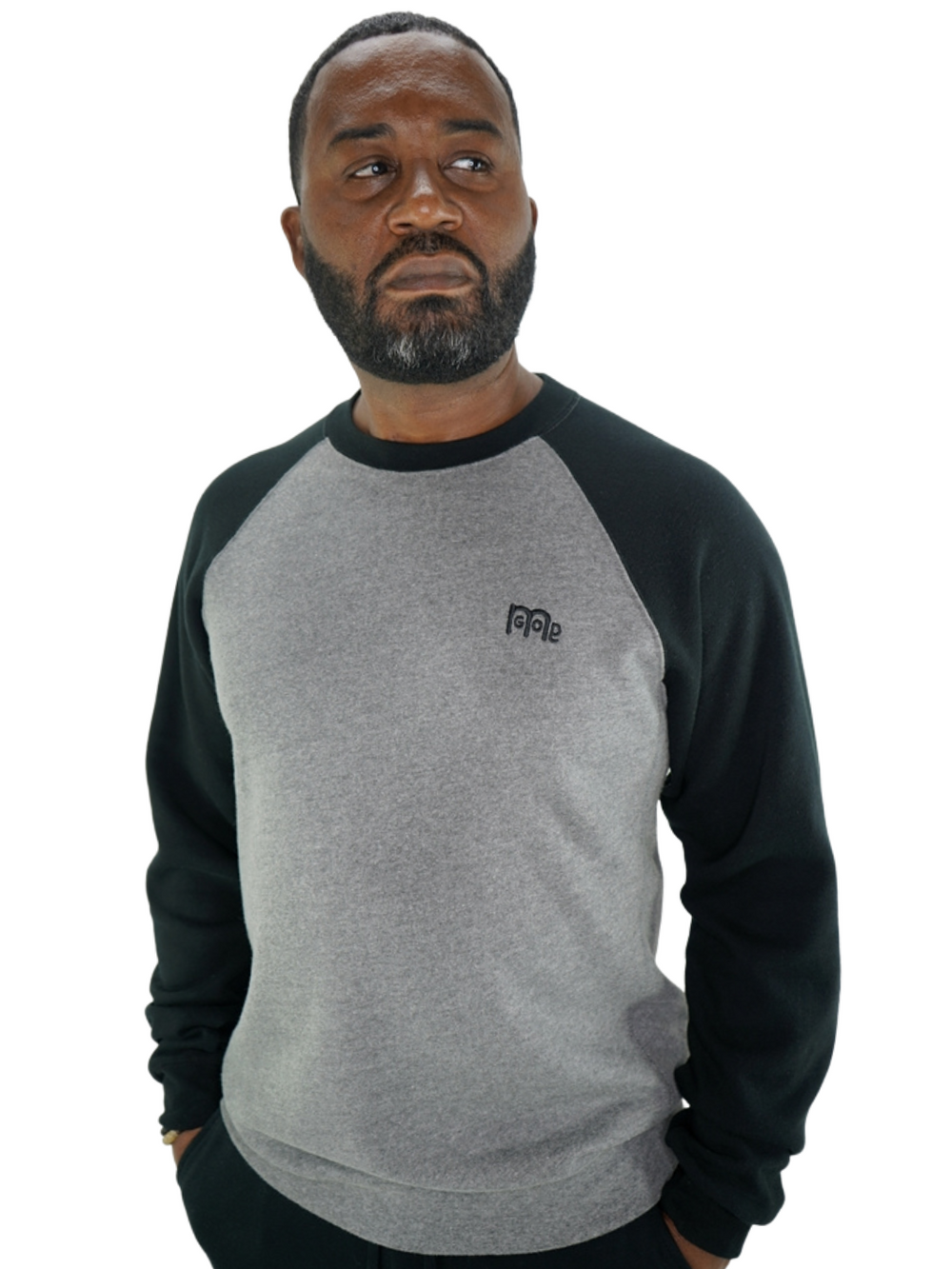 Model wearing GODinme Crewneck Sweater with Black raglan sleeves, Grey mid-section, and Black embroidered GODinme logo at left chest.