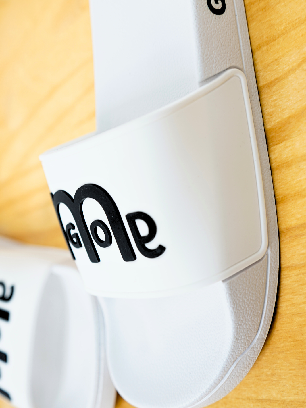 Women's White GODinme Slides feature an embossed Black GODinme logo on front and signature Black GODinme on the outside heels.