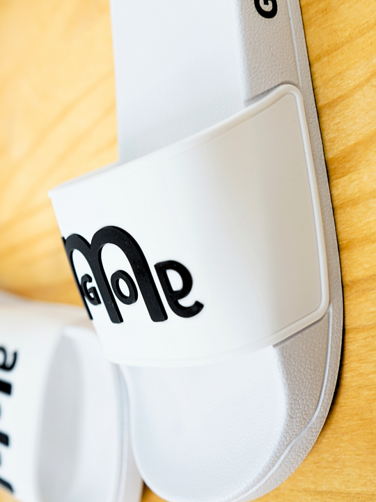 Women's White GODinme Slides feature an embossed Black GODinme logo on front and signature Black GODinme on the outside heels.